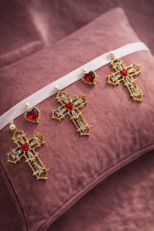 Cross My Heart Jeweled Charm Bridal Choker flat lay with white ribbon, ornate gold cross charms, red jeweled heart charms, and pearls on a blush velvet pillow