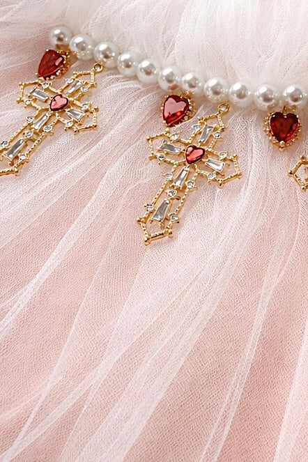 Close-up detail of a gold cross charm with red jeweled heart accent on the Cross My Heart Jeweled Charm Wedding Veil