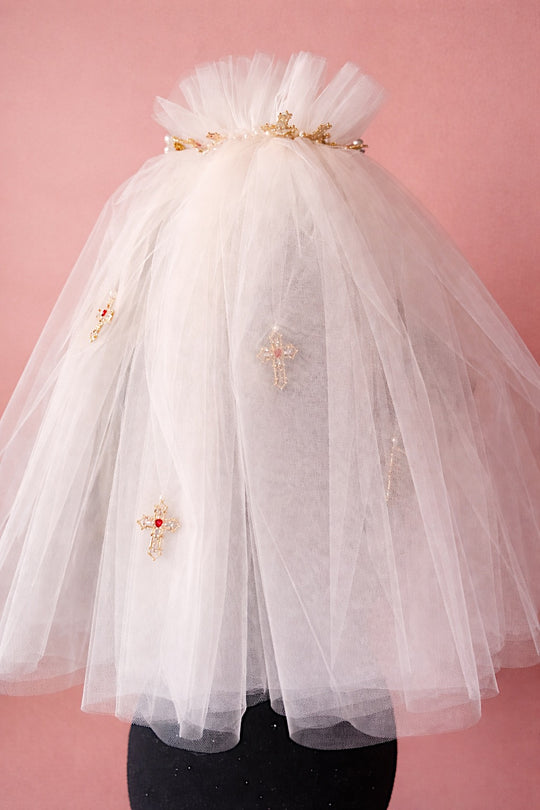 Ivory Cross My Heart Jeweled Charm Wedding Veil with gold cross charms and jeweled heart details against a blush backdrop