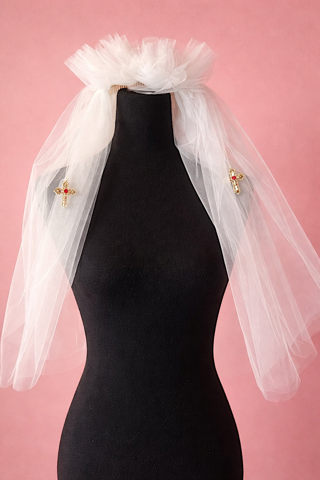 Cross My Heart Jeweled Charm Wedding Veil displayed on a black mannequin against a blush backdrop
