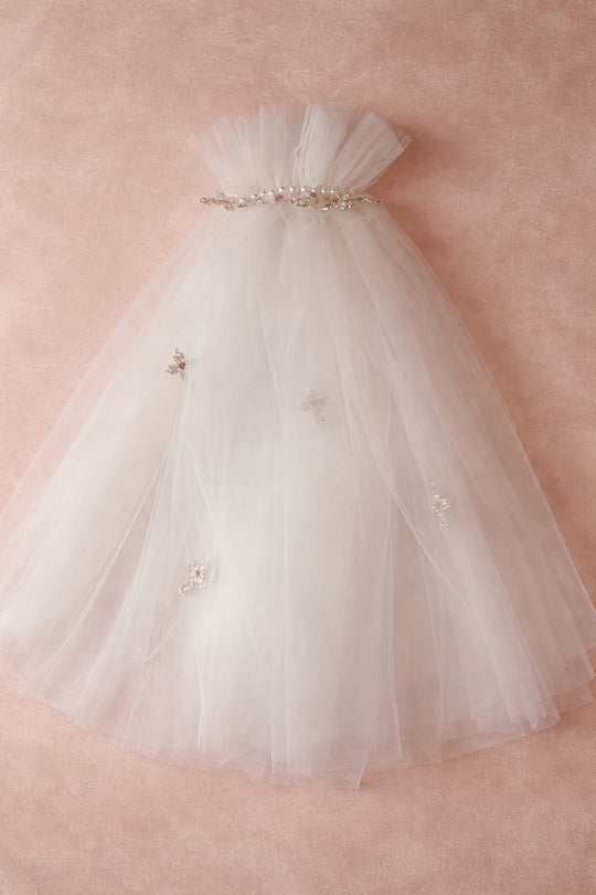 Ivory Cross My Heart Jeweled Charm Wedding Veil flat lay with gold cross charms and jeweled heart details against a blush velvet backdrop