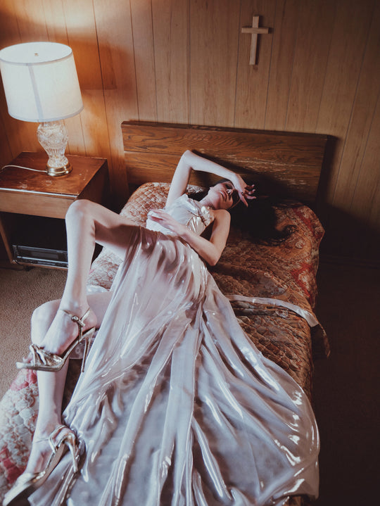 Wuthering Hearts metallic chiffon wedding gown draped across a vintage bed with flowing full skirt and slit