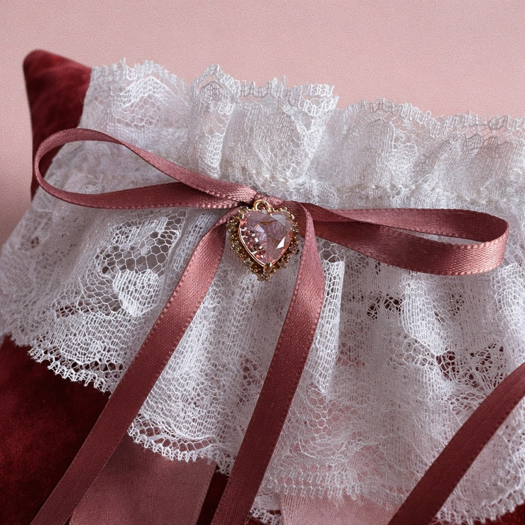 Close-up of blush satin bow wedding garter with blackletter typography ribbon