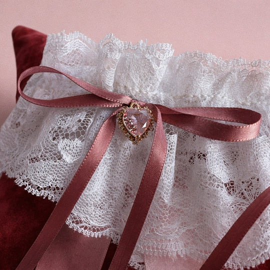 Close-up of blush satin bow wedding garter with blackletter typography ribbon