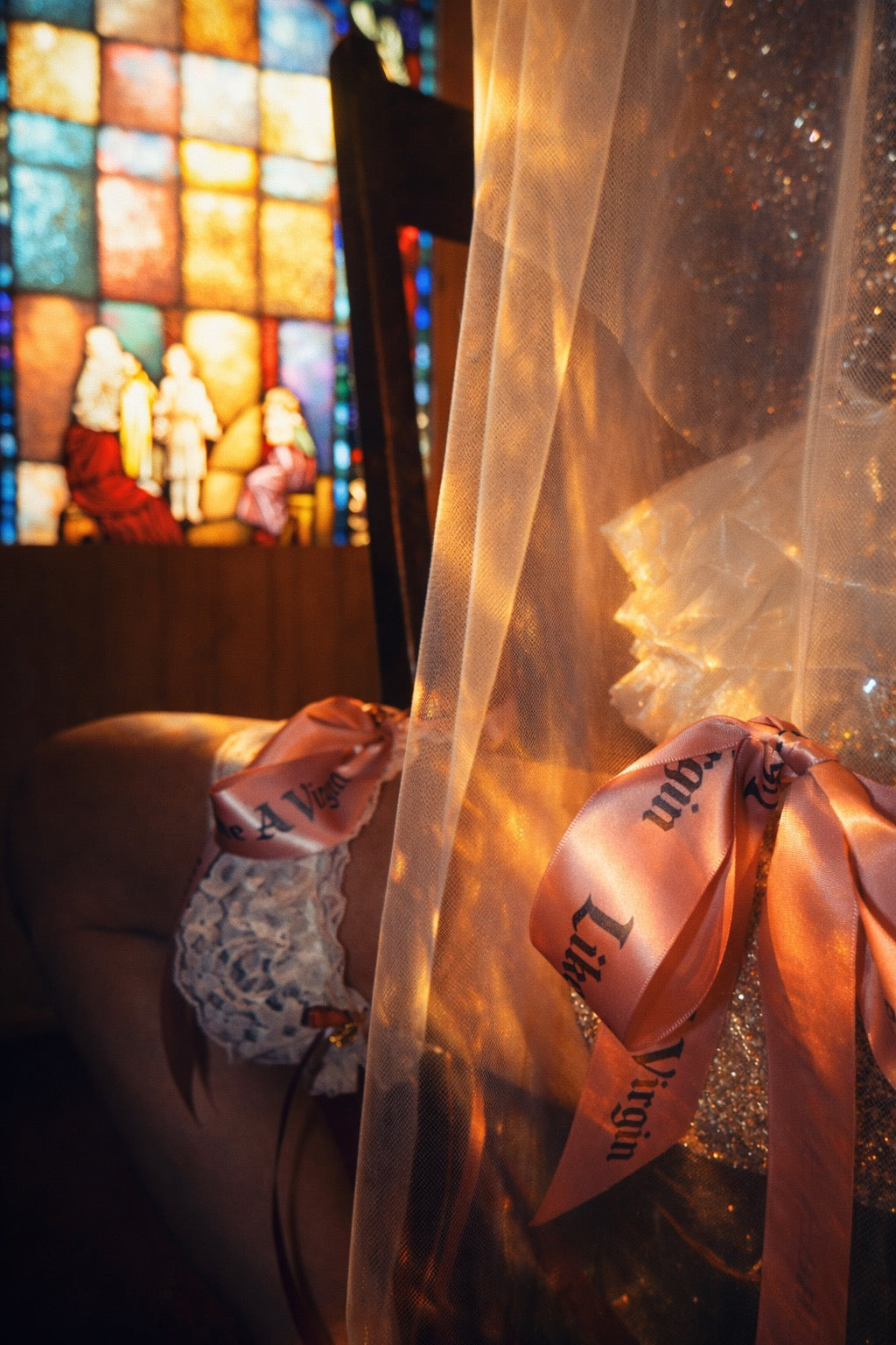 Close-up of satin bow bridal garter with blackletter typography ribbon and stretch lace band