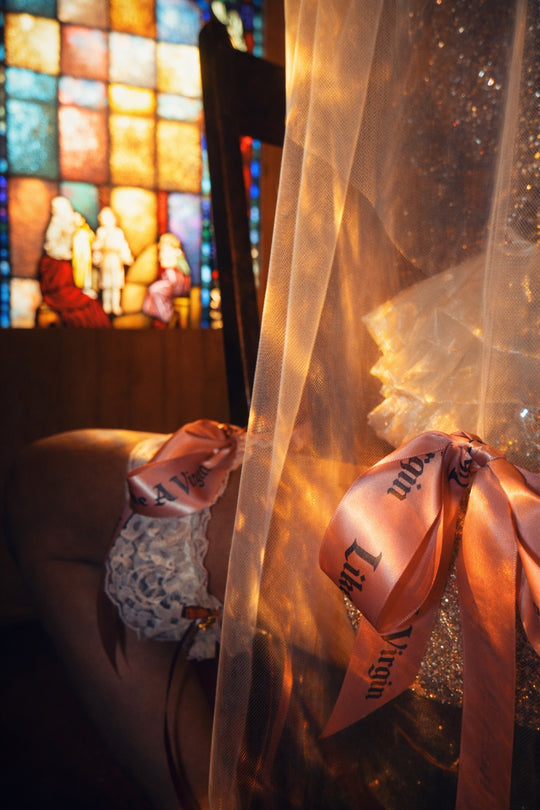 Close-up of satin bow bridal garter with blackletter typography ribbon and stretch lace band