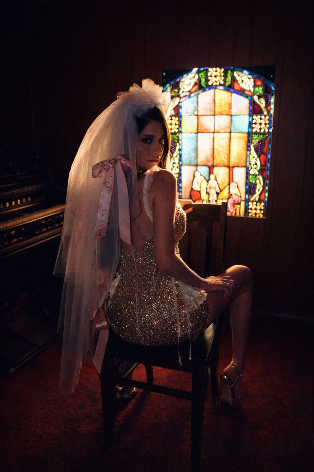 Modern bride wearing Like A Virgin statement wedding veil with blush satin ribbon bows in moody chapel setting