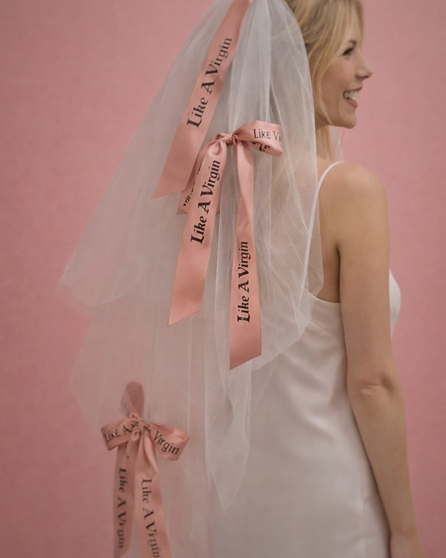 Like A Virgin satin bow wedding veil with blush printed ribbon bows styled on modern bride against pink backdrop