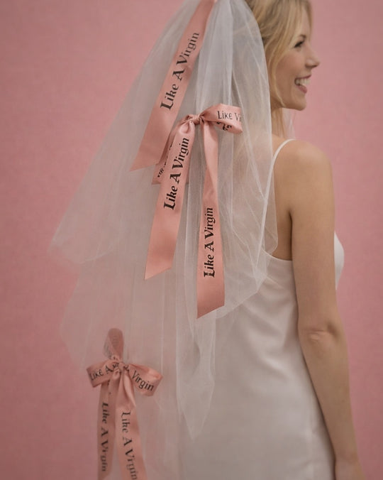 Like A Virgin satin bow wedding veil with blush printed ribbon bows styled on modern bride against pink backdrop