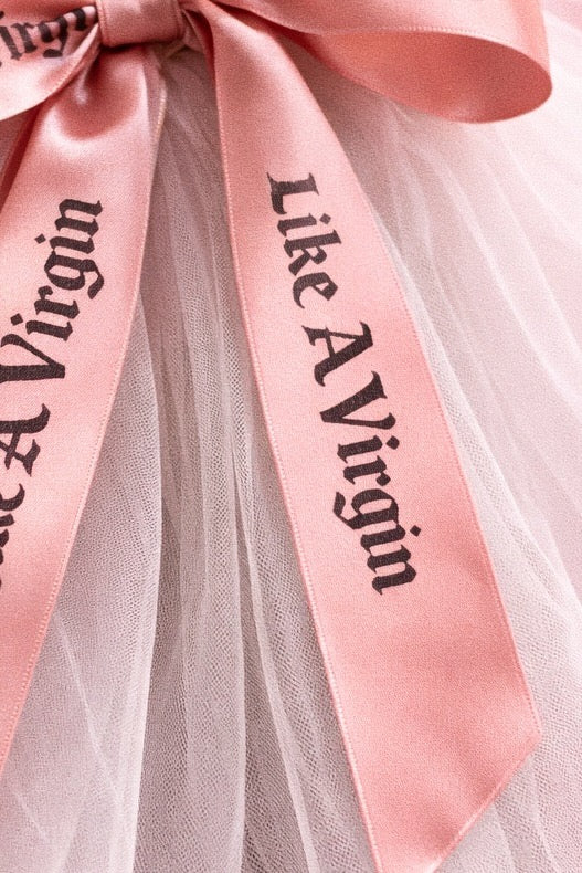 Close detail of blush satin bow wedding veil with Like A Virgin printed ribbon on sheer tulle