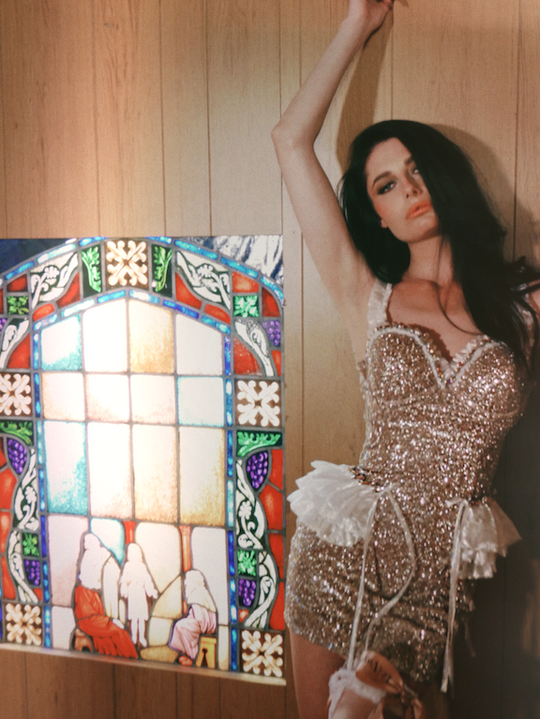 A brunette bride in sparkly mini wedding dress posing beside stained glass window.